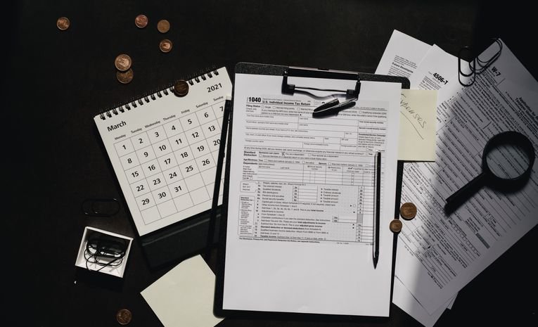 Person filling out financial paperwork with a calculator, representing setting up an HMRC business tax account