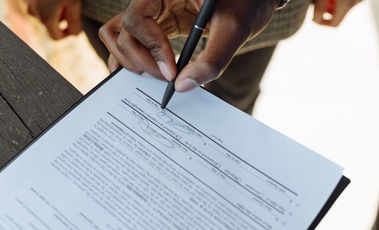 Close-up of a person signing a legal document, representing the process of registering a business trademark